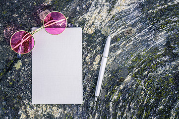 Image showing Pink sunglasses and blank paper on mossy stone background