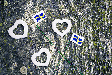Image showing Swedish flags and white hearts on mossy rock background