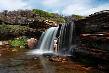 Image showing Happy woman standing under a waterfall in bushland wilderness