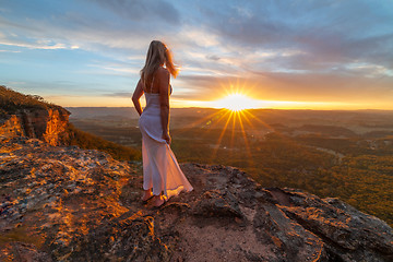 Image showing Woman watching blissful sunsets from hidden cliff ledges