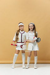 Image showing Portrait of two girls as tennis players holding tennis racket. Studio shot.