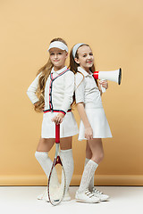 Image showing Portrait of two girls as tennis players holding tennis racket. Studio shot.