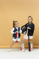 Image showing Portrait of two girls as tennis players holding tennis racket. Studio shot.