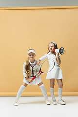 Image showing Portrait of two girls as tennis players holding tennis racket. Studio shot.