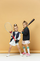 Image showing Portrait of two girls as tennis players holding tennis racket. Studio shot.