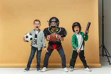 Image showing Three happy children show different sport. Studio fashion concept. Emotions concept.