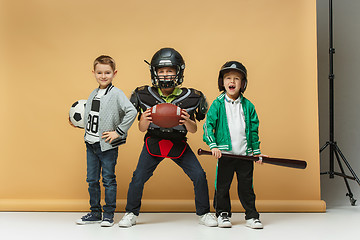 Image showing Three happy children show different sport. Studio fashion concept. Emotions concept.