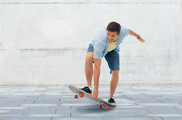 Image showing young man riding skateboard over urban background