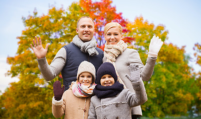 Image showing happy family waving hands over autumn park