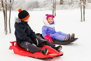 Image showing happy little kids sliding on sleds in winter