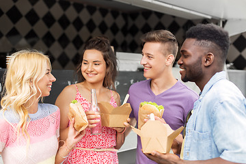 Image showing happy friends with drinks eating at food truck