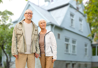 Image showing happy senior couple holding hands over house