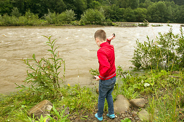 Image showing Little boy throwing stones in the water