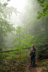 Image showing Mother and son in the mystic green foggy forest. The are looking