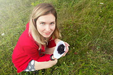 Image showing Woman collecting blackberry in the meadow. Happy woman and wild 