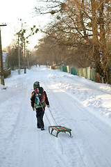 Image showing Little boy is carrying sleigh