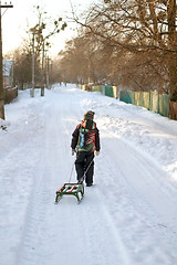 Image showing Little boy is carrying sleigh