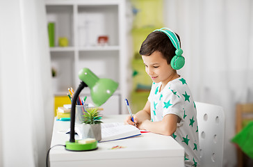 Image showing boy in headphones with textbook learning at home