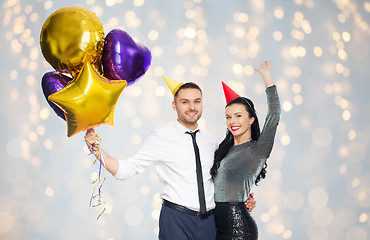 Image showing happy couple in party hats with balloons