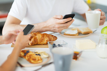 Image showing close up of couple with smartphones at breakfast