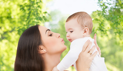 Image showing mother kissing baby over green natural background