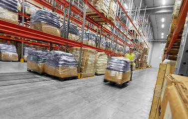 Image showing worker carrying loader with goods at warehouse