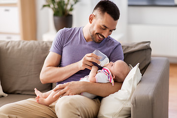 Image showing father feeding baby daughter from bottle at home