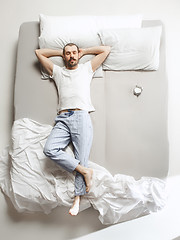 Image showing Top view photo of young man sleeping in a big white bed