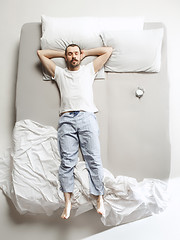 Image showing Top view photo of young man sleeping in a big white bed