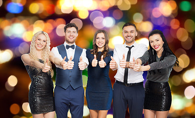 Image showing happy friends in party clothes showing thumbs up