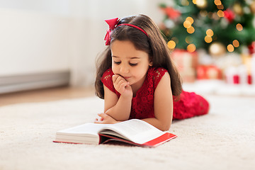 Image showing happy girl reading book at home on christmas