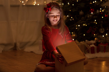 Image showing smiling girl opening christmas gift at night