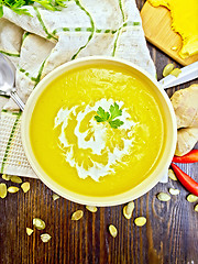 Image showing Soup-puree pumpkin with cream and parsley in bowl on board top