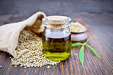 Image showing Oil hemp in jar with flour on dark board