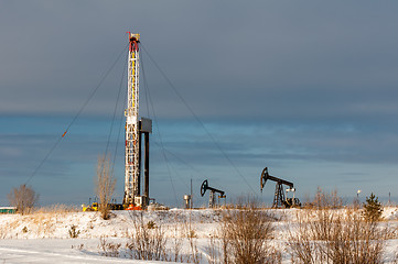 Image showing Oil field. Drilling rig and oil pump.