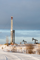 Image showing Oil field. Drilling rig and oil pump.