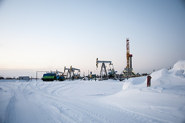 Image showing Oil field. Drilling rig and oil pump.