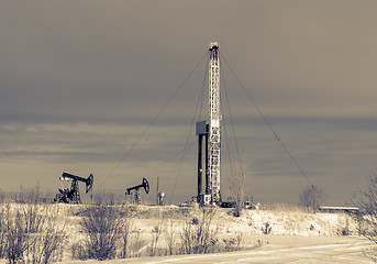 Image showing Oil field. Drilling rig and oil pump.