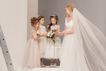 Image showing Little pretty girls with flowers dressed in wedding dresses