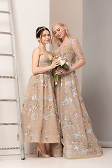Image showing Brides in beautiful dress standing indoors in white studio interior like at home. Trendy wedding style shot. Young attractive caucasian model like a bride tender looking.