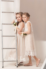 Image showing Little pretty girls with flowers dressed in wedding dresses