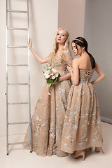 Image showing Brides in beautiful dress standing indoors in white studio interior like at home. Trendy wedding style shot. Young attractive caucasian model like a bride tender looking.