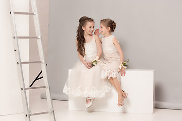 Image showing Little pretty girls with flowers dressed in wedding dresses