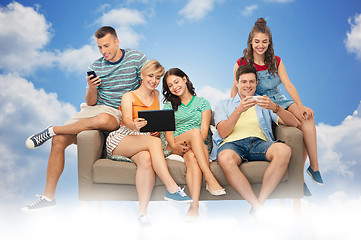 Image showing friends with tablet pc and smartphones sit on sofa