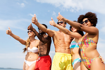 Image showing happy friends showing thumbs up on summer beach