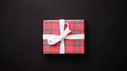 Image showing Red gift box with white bow on black table, top view