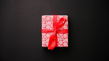 Image showing Red gift box with red bow on black table, top view