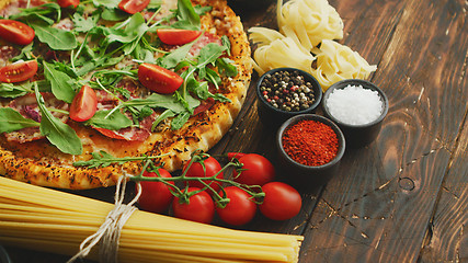 Image showing Italian food background with pizza, raw pasta and vegetables on wooden table