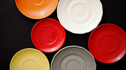 Image showing Colorful empty plates and saucers over black background.