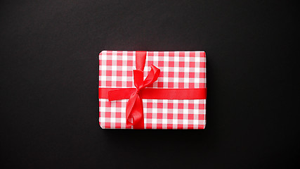 Image showing Red gift box with red bow on black table, top view